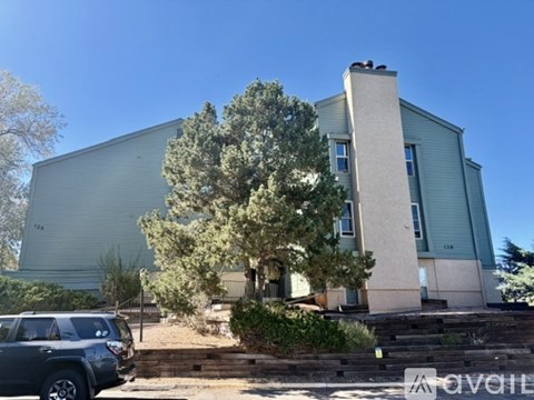 A grey building with a tree in front of it.