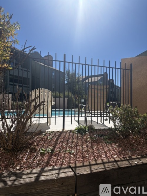 A pool surrounded by a metal fence and some plants.