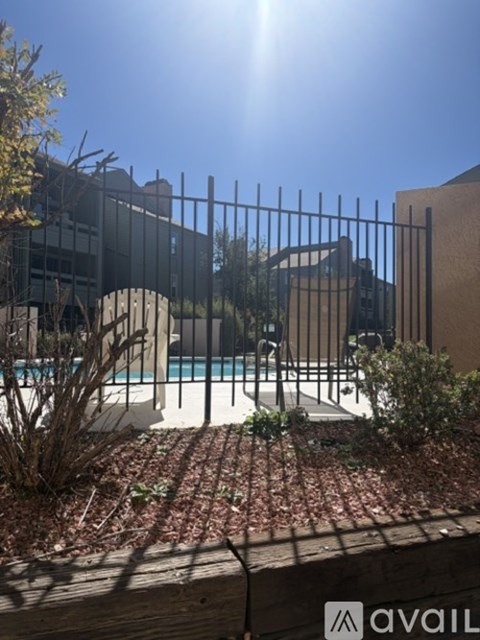 A pool surrounded by a metal fence and some plants.