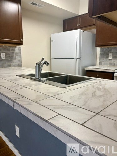 A kitchen with a white fridge and a marble counter top.