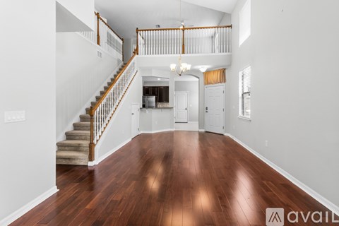 A spacious living room with hardwood floors and a staircase with wooden railings.