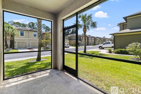 A view from inside a house looking out through a sliding glass door at a street with houses and palm trees.