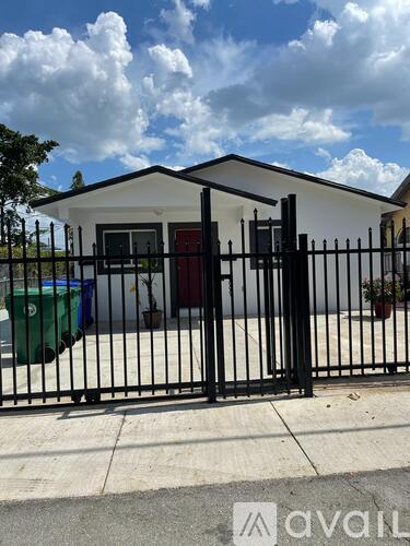 A black metal fence surrounds a white house.