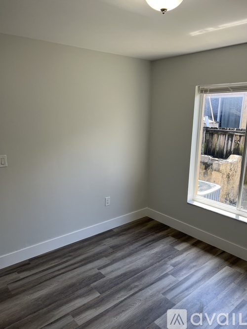 A room with a window and wooden flooring.