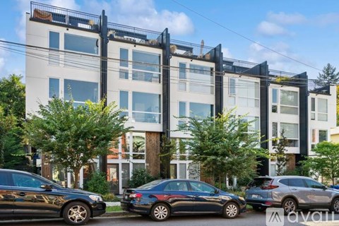 A modern multi-story building with cars parked in front.