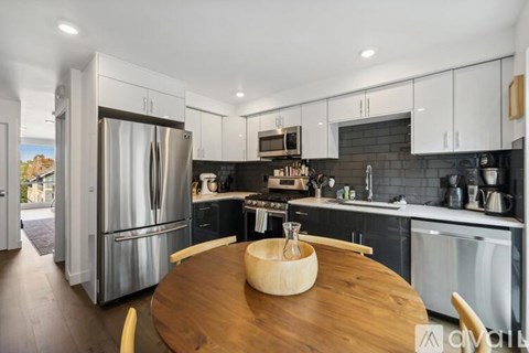 A modern kitchen with a wooden table and stainless steel appliances.