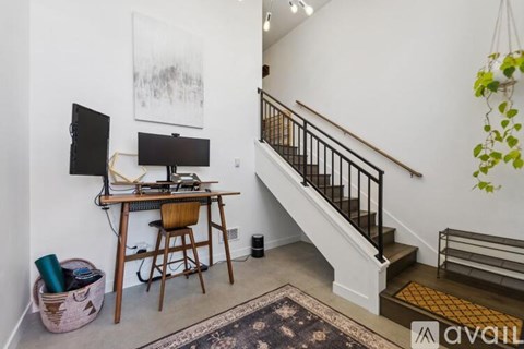 A room with a staircase and a desk with a computer.