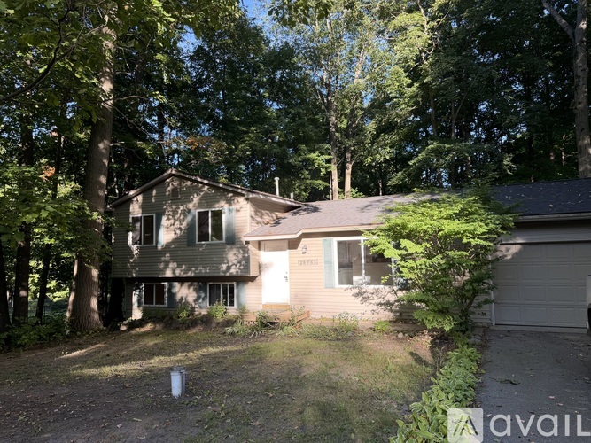 A house with a garage is surrounded by trees.