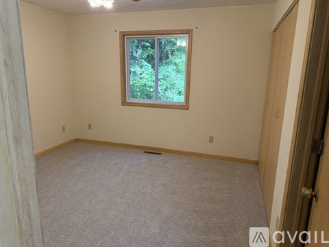A room with a window showing greenery outside.