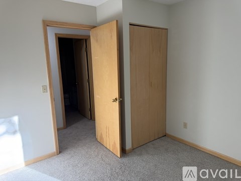 A room with a carpeted floor and two wooden doors.