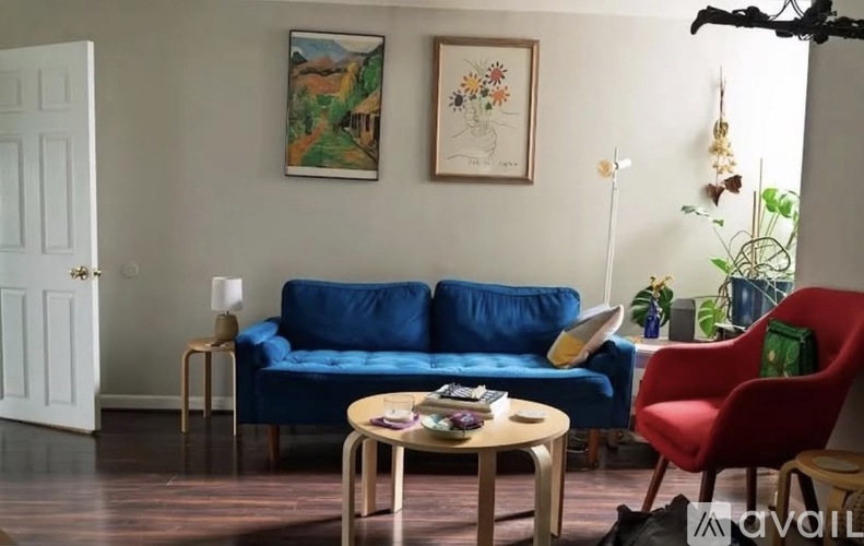 A living room with a blue couch, a red chair, and a wooden coffee table.