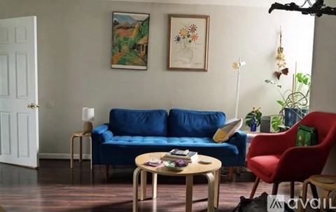 A living room with a blue couch, a red chair, and a wooden coffee table.