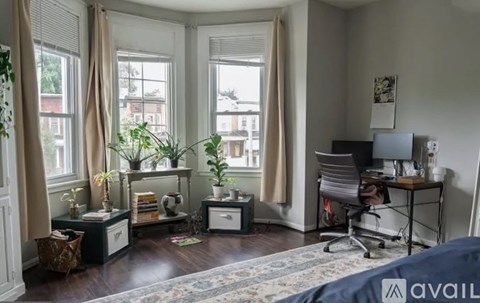 A room with a desk, chair, and window with curtains.