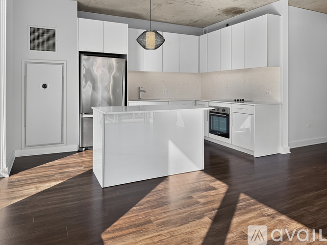 A modern kitchen with white cabinets and a wooden floor.