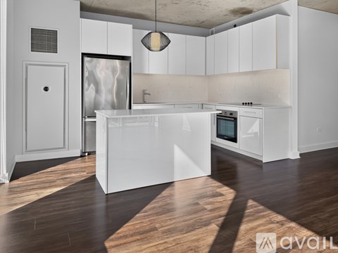 A modern kitchen with white cabinets and a wooden floor.