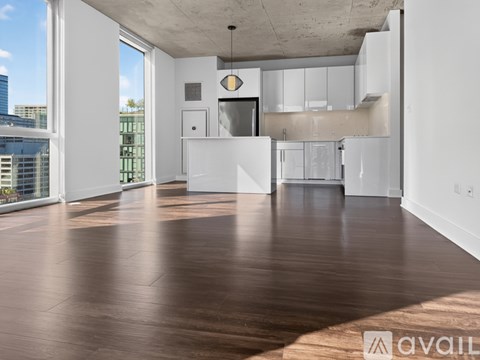 A spacious, empty room with wooden floors and white walls.