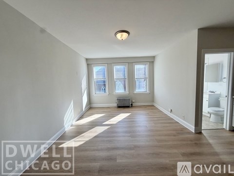 A spacious room with a radiator and a window with a view of a city.
