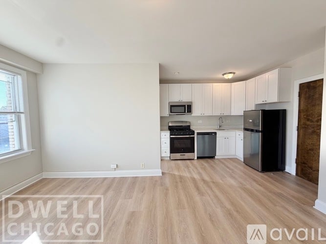 A kitchen with white cabinets and a black refrigerator.