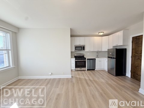 A kitchen with white cabinets and a black refrigerator.