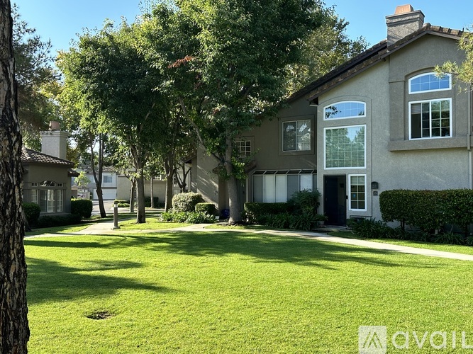 A house with a green lawn and trees in the background.