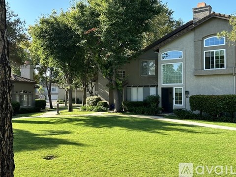 A house with a green lawn and trees in the background.