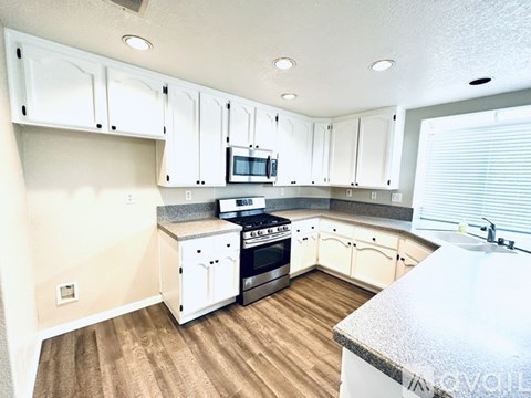 A kitchen with white cabinets and a wooden floor.