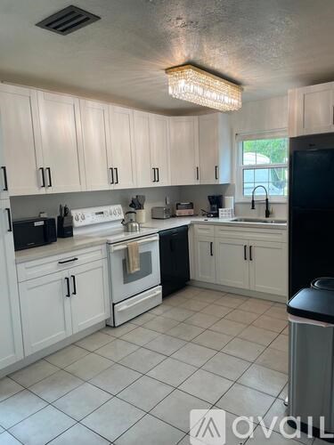 A kitchen with white cabinets and black appliances.
