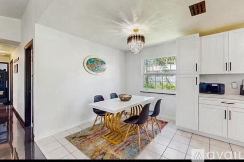 A dining room with a white table and chairs.