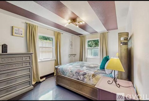 A bedroom with a bed, dresser, and window with curtains.