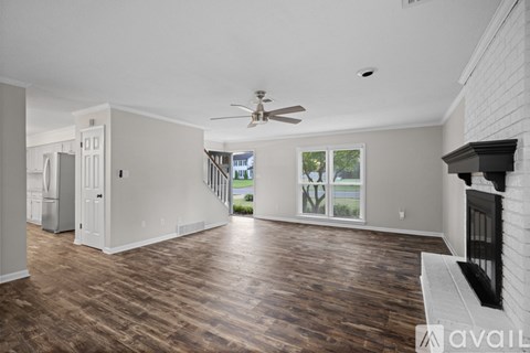 A spacious living room with wood flooring and a ceiling fan.