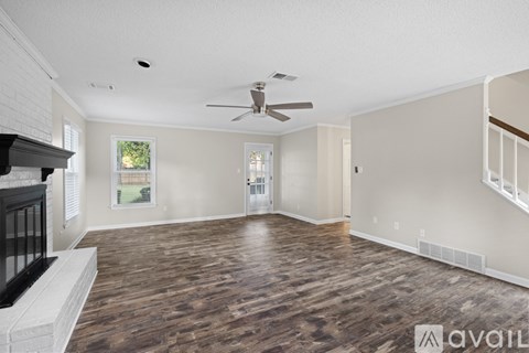 A spacious room with a fireplace on the left and a ceiling fan above the center of the room.