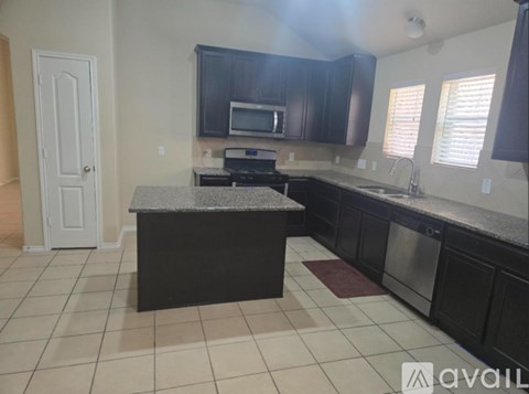 A kitchen with black cabinets and a granite countertop.