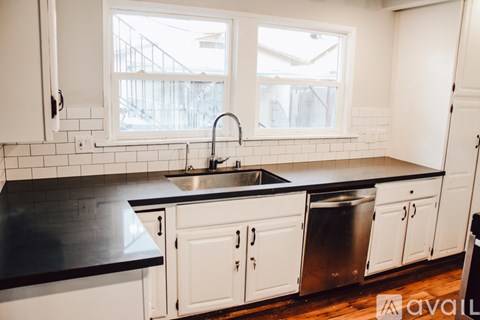 A kitchen with white cabinets and a black countertop.