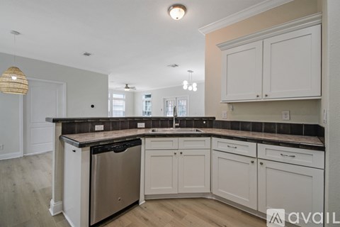 A kitchen with white cabinets and a black countertop.