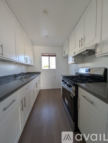A kitchen with white cabinets and a black stove top oven.
