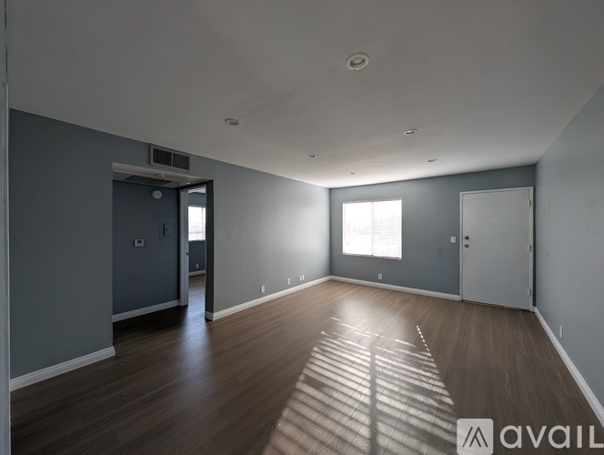 A spacious room with wooden floors and a large window.