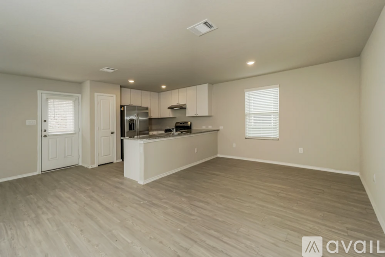 A spacious kitchen with white cabinets and a wooden floor.