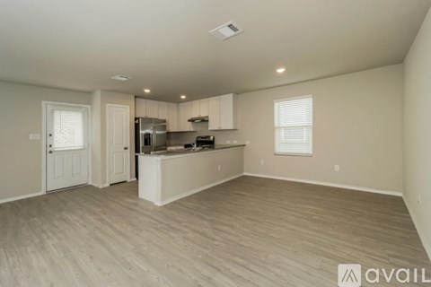 A spacious kitchen with white cabinets and a wooden floor.