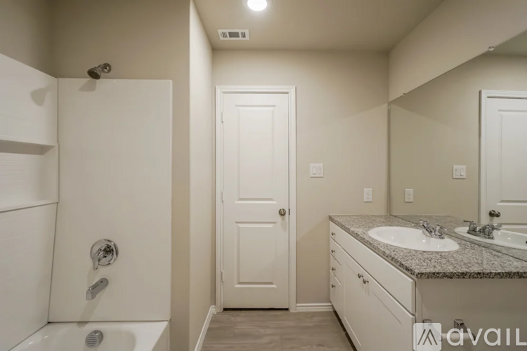 A bathroom with a white tub, sink, and door.