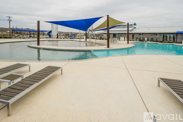 A pool with sun loungers and a blue shade structure.