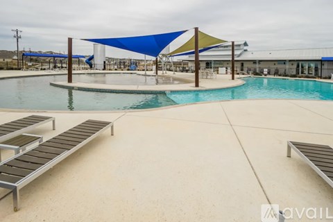 A pool with sun loungers and a blue shade structure.
