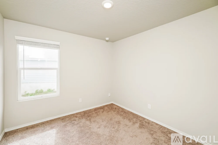 A room with a window and a carpeted floor.