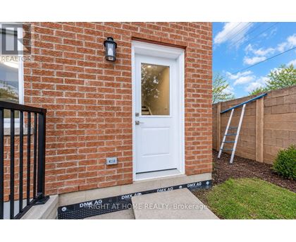 A red brick house with a white door and a black gate.
