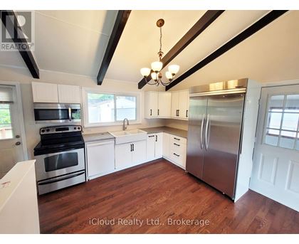 A kitchen with stainless steel appliances and wooden floors.