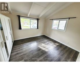 A room with wooden flooring and two windows with black frames.