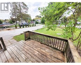 A wooden deck overlooks a grassy area and a parking lot.