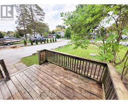 A wooden deck overlooks a grassy area and a parking lot.