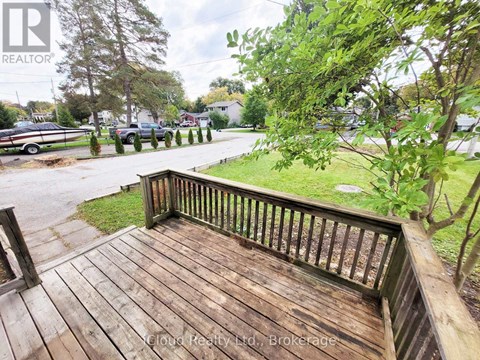 A wooden deck overlooks a grassy area and a parking lot.