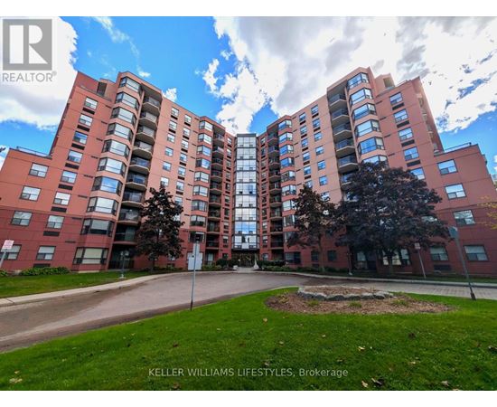 A large brick apartment building with a green lawn in front.
