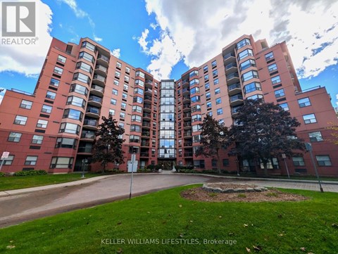 A large brick apartment building with a green lawn in front.